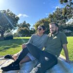 Man and woman sitting down at park wearing solstice gear