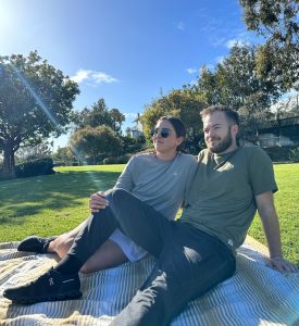 Man and woman sitting down at park wearing solstice gear